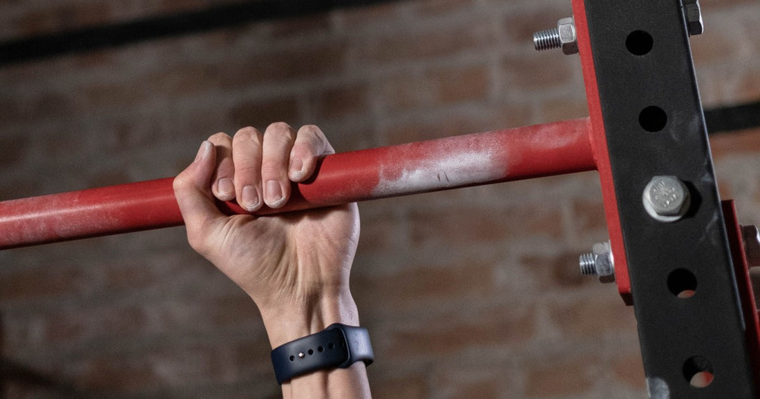 Chalked hand gripping a pull-up bar in a gym