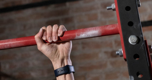 Chalked hand gripping a pull-up bar in a gym