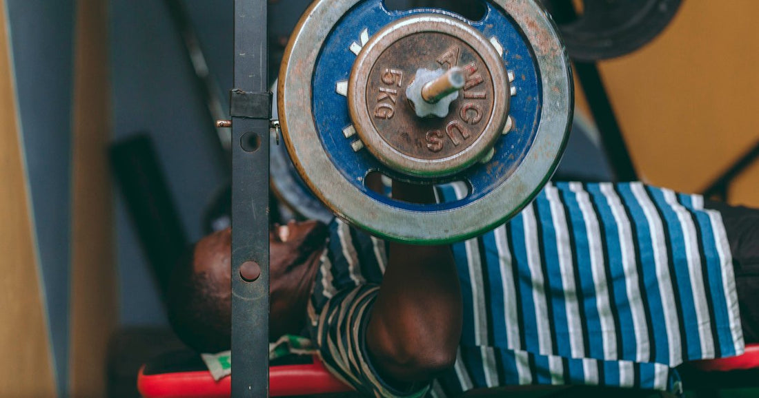 Lifter lying on a flat bench pressing a loaded barbell in an indoor gym